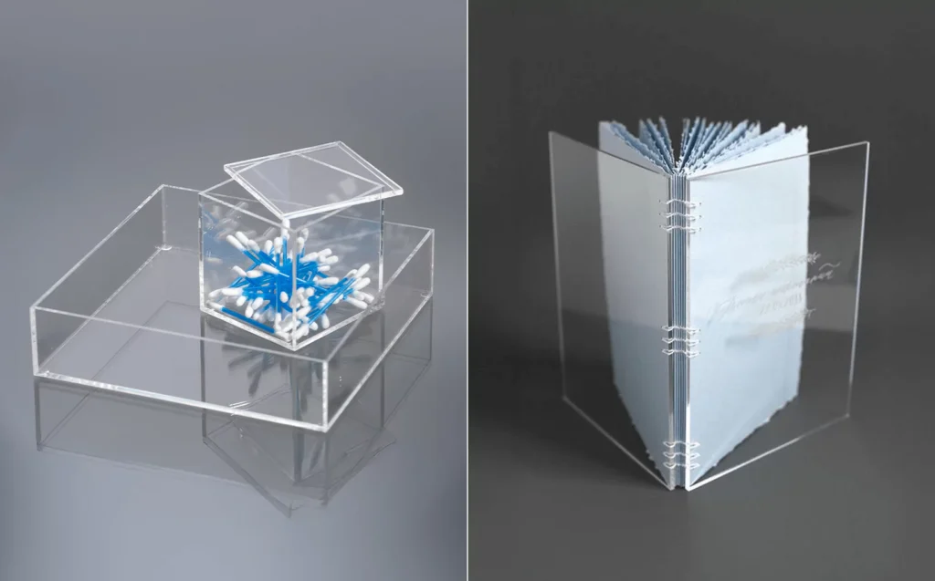 Clear plexiglass Q-tip holder and an acrylic-bound book with transparent covers on a dark surface.