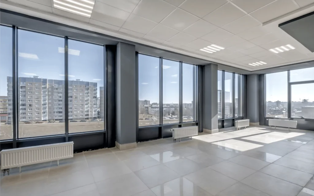 Spacious empty office with floor-to-ceiling windows offering a clear cityscape view.