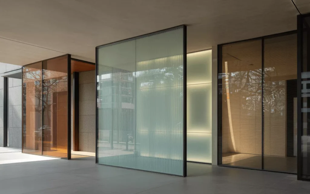 Low-iron, tinted, Low-E, fire-rated, and smart glass types shown in a bright modern space, highlighting clarity and innovation.