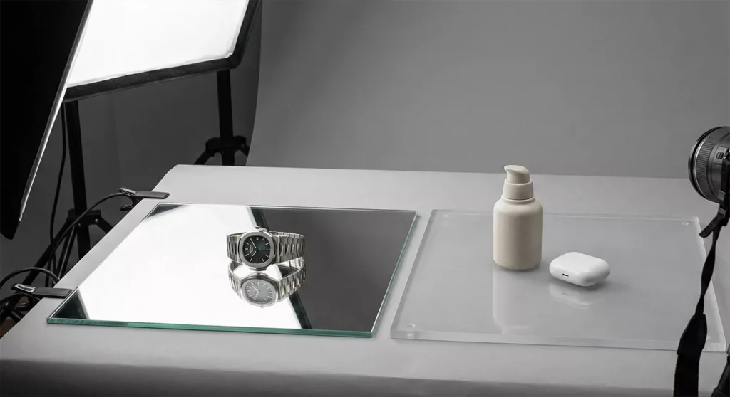 Real-world product shoot showing glass vs acrylic surfaces with luxury and everyday items and natural reflections.