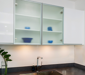 Contemporary kitchen with glass-front cabinets showcasing frosted or decorative glass, adding a stylish touch to the space.