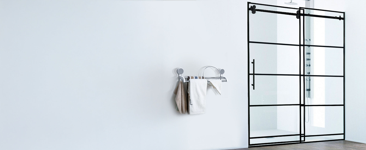 Industrial style bathroom with black grid framed sliding shower doors and towel rack on white wall.