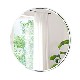 Round wall mirror reflecting bright window view with indoor plants