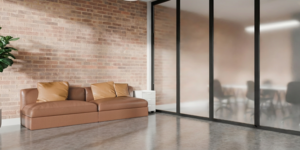 Frosted glass panel room divider beside a brown leather sofa in a modern office