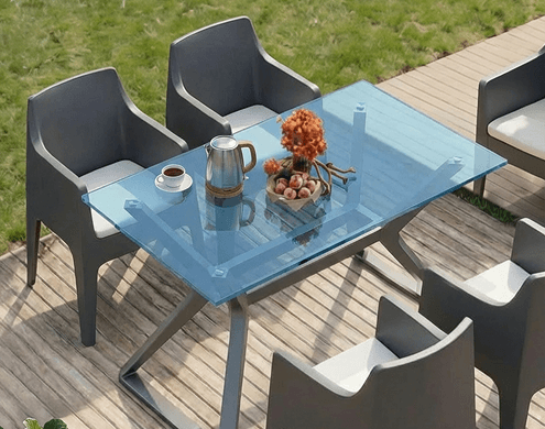 Elegant outdoor dining table featuring a sleek blue tinted glass top.