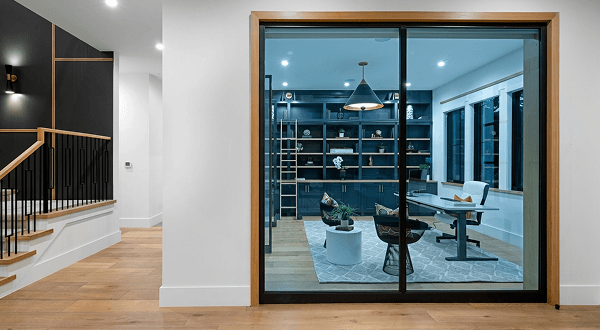 Open black-framed glass doors revealing a modern home office with blue tinted glass panels.