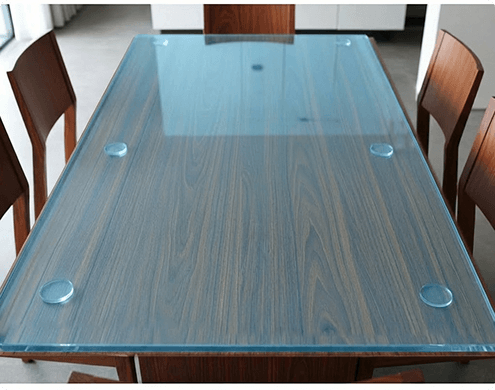 Rectangular wooden dining table topped with clear blue tinted tempered glass.