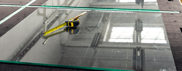 Professional measurement of tempered glass panels, highlighting accurate custom cut precision for every order.