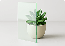 Clear tempered glass sample showcasing high transparency and custom cut precision against a small plant.