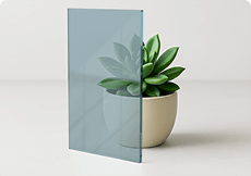 Blue tinted tempered glass sample showcasing its cool hue and custom cut precision against a small plant. 