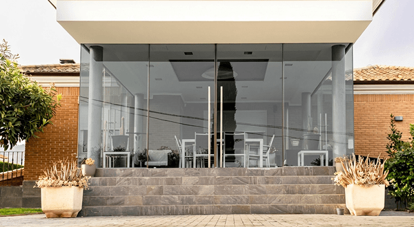 Contemporary house facade with large floor-to-ceiling ECL grey tempered glass walls and doors.