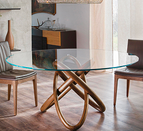 Round glass dining table with artistic wooden base in a modern dining room setting.