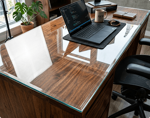 Rectangular glass office desk with chrome base surrounded by white leather chairs in boardroom