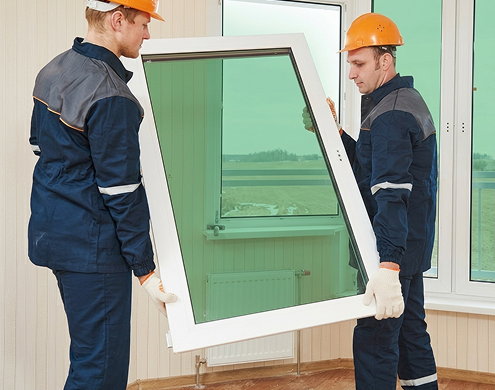 Professional installation of light green tempered glass window by skilled workers in safety gear