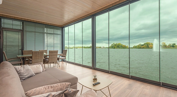 Spacious living room featuring elegant green tempered glass windows overlooking the lake