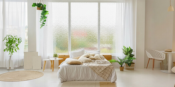 Cozy bedroom with Spraylite Tempered Glass on large bright windows