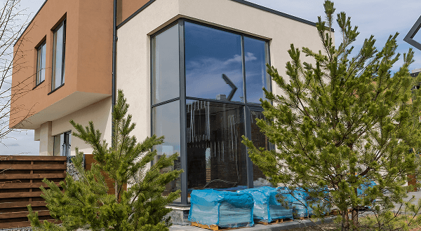 Exterior view of a contemporary building with large Super Grey glass windows and dark frames surrounded by greenery.