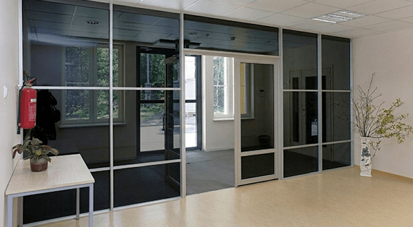 Professional office space with super grey tempered glass room dividers and sliding doors in a bright interior setting.