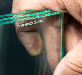 Close-up of a hand holding tempered glass sheets showing thickness and edge clarity.